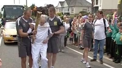 Andy Seward leaves his wheelchair to carry the Olympic flame