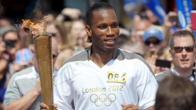 Didier Drogba runs with the Olympic torch along Market Street in Swindon, Wiltshire