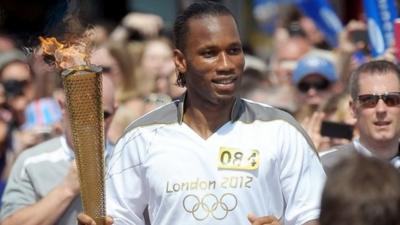 Didier Drogba runs with the Olympic torch along Market Street in Swindon, Wiltshire