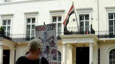 A protester holds a sign outside the Embassy of the Syrian Arab Republic in central London