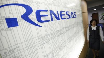 Worker next to logo of chipmaker Renesas Electronics