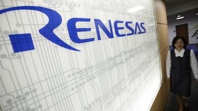 Worker next to logo of chipmaker Renesas Electronics