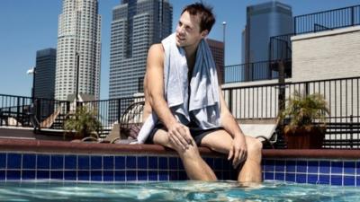 man sitting by side of roof swimming pool