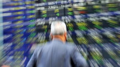 A businessman gazes at a share prices board in Tokyo