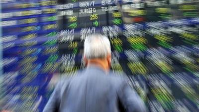 A businessman gazes at a share prices board in Tokyo