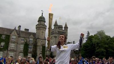 Lauren Fraser lifts the Olympic torch in front of Balmoral Castle