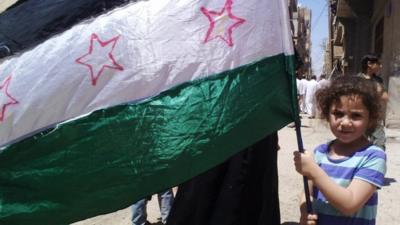 A girl holding the Syrian revolutionary flag