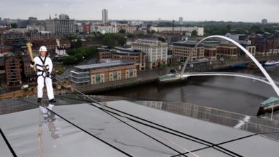 Richard Jackson abseils down the Sage Gateshead with the Olympic flame