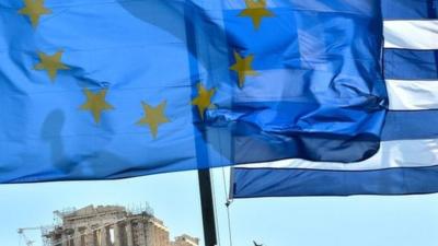 EU and Greek flags float in front of the Acropolis in central Athens