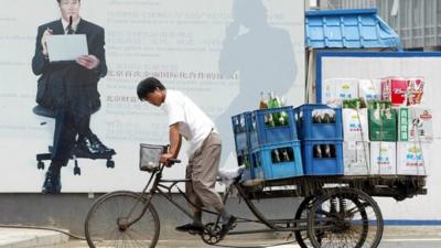 A man hauls a tricycle load of beer in Beijing's central business district, China