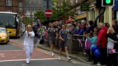 Woman carries the Olympic torch through Dumfries