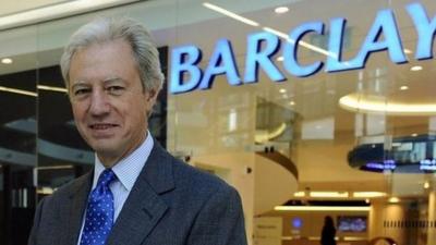 Man standing in front of Barclays sign