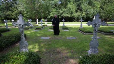 A monk stands in a graveyard