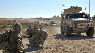 Husky protected support vehicle with British Troops on foot patrol in Afghanistan.