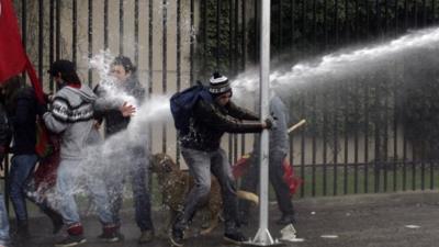 Demonstrators are hit by a jet of water as they clash with riot policemen in Chile