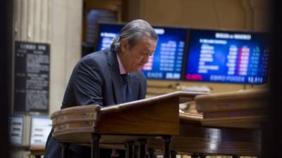 A broker looks at some papers at the Stock Exchange in Madrid