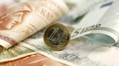 A one Euro coin is displayed on Greek Drachma and Euro banknotes