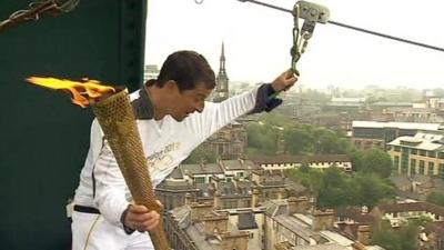 Bear Grylls with the Olympic Torch about to take a zip wire across the Tyne