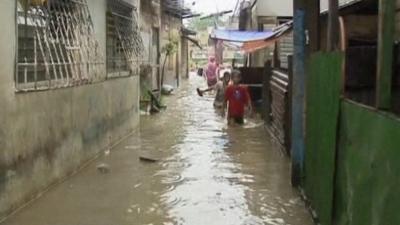 Children walking through waist-deep water on a street