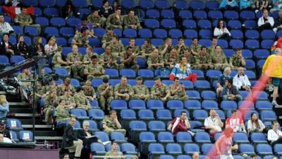 Members of the military sit in unoccupied sponsors seats during the artistic gymnastics team qualification