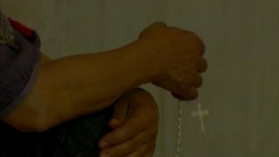 Christian refugee holding prayer beads