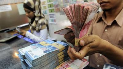 Bank teller with Indonesian rupiah notes