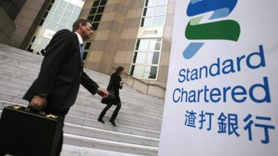 People walk outside the main branch of the Standard Chartered Bank in Hong Kong