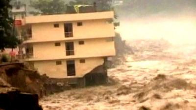 River flowing past partially collapsed housing block in India