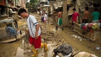 Local residents return to their homes and start to clean up the mud left after the floods in San Mateo town, Rizal province east of Manila.