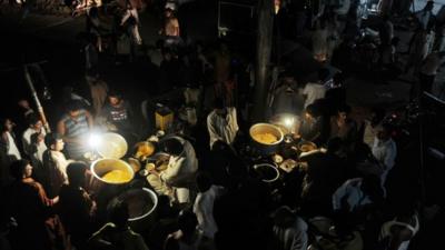 Pakistani vendors sell food under the lights of gas lamps during a power cut in Lahore