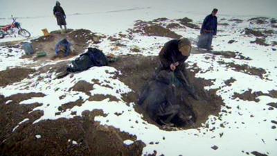 Mine workers enter small holes in the ground to mine for gold