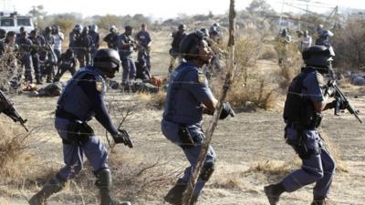 Policemen react after firing shots at protesting miners outside a South African mine in Rustenburg