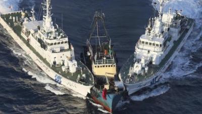 A boat, centre, is surrounded by Japan Cost Guard patrol boats after some activists jumped from the boat on 15 August, 2012