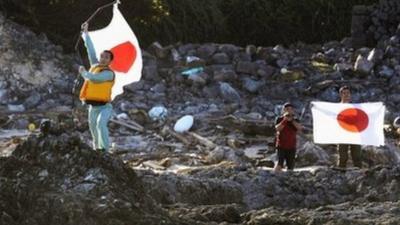 Members of a Japanese nationalist group raise Japanese flags after landing on disputed islands