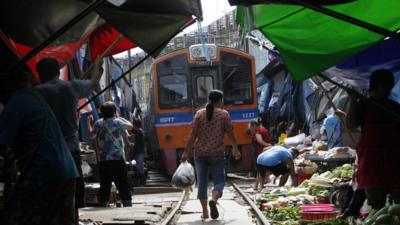 Thai market sellers pull their produce off a railway track to allow a train to pass through in the town of Maeklong