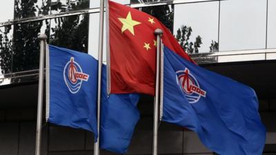 China National Offshore Oil Corp flags and China's flag in front of CNOOC's Beijing headquarters