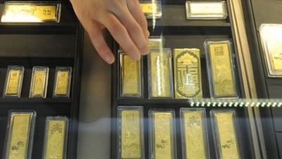 In a picture taken on March 2, 2011 a Chinese sales assistant arranges gold bars at a gold jewellery shop in Hefei.