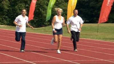 Three people running on athletics track