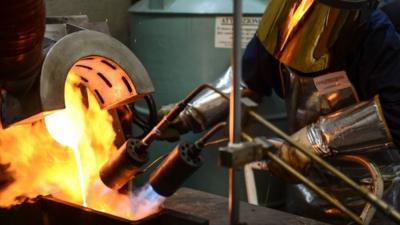 A goldsmith controlling the fire during the melting of gold to produce a gold ingot