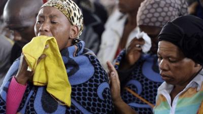 A woman mourns during a memorial service for the 44 people killed in a wildcat strike at Lonmin's Marikana mine on 22 August 2012 in Marikana, South Africa