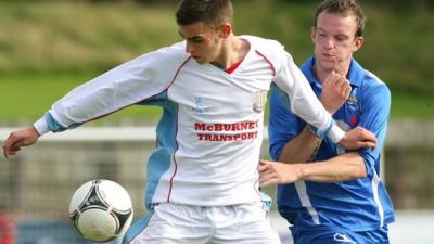 Jamie Davidson of Ballymena shields the ball from Ballinamallard's Chris Curran