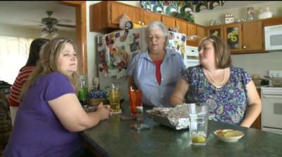 Three women sit at a kitchen table