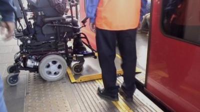 A wheelchair user getting on a Tube train with a ramp