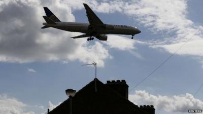 An airplane comes in over the top of houses to land at Heathrow Airport in west London