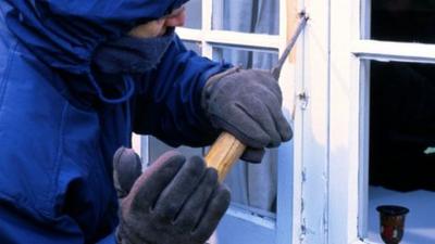 A masked hooded man appears to break into a house