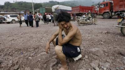 Man sits surrounded by rubble