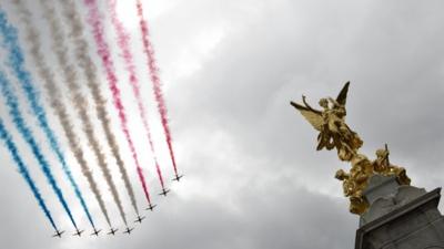 The British Royal Air Force Red Arrows display team fly past the Queen Victoria Memorial in front of Buckingham Palace after a parade