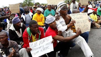 Miners hold placards as police stop them from proceeding with their march in Rustenburg, South Africa