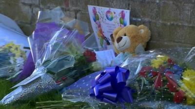 Floral tributes are laid close to where the three family members died.