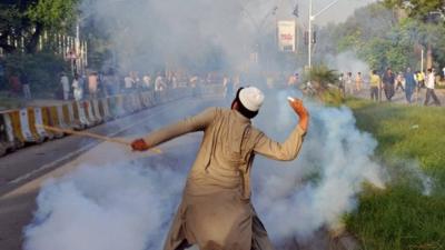 Protester throwing tear gas shell back at police